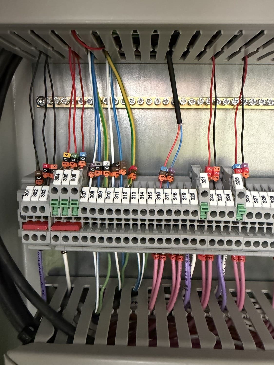 Numbered DIN-rail terminal blocks with marker-sleeved control wiring and an earth bar inside a panel